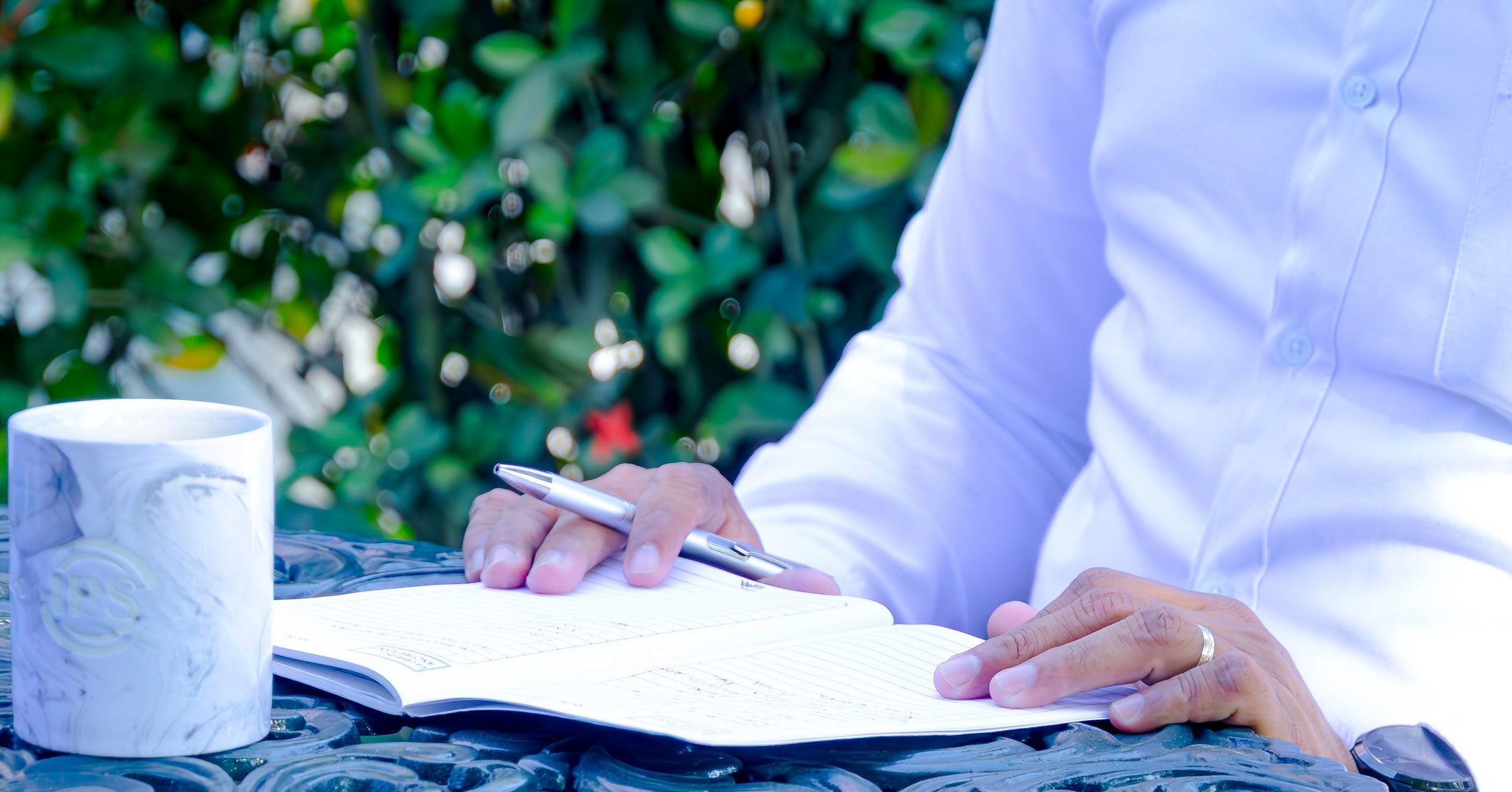Executive taking notes in a notebook beside a Grupo IPS mug