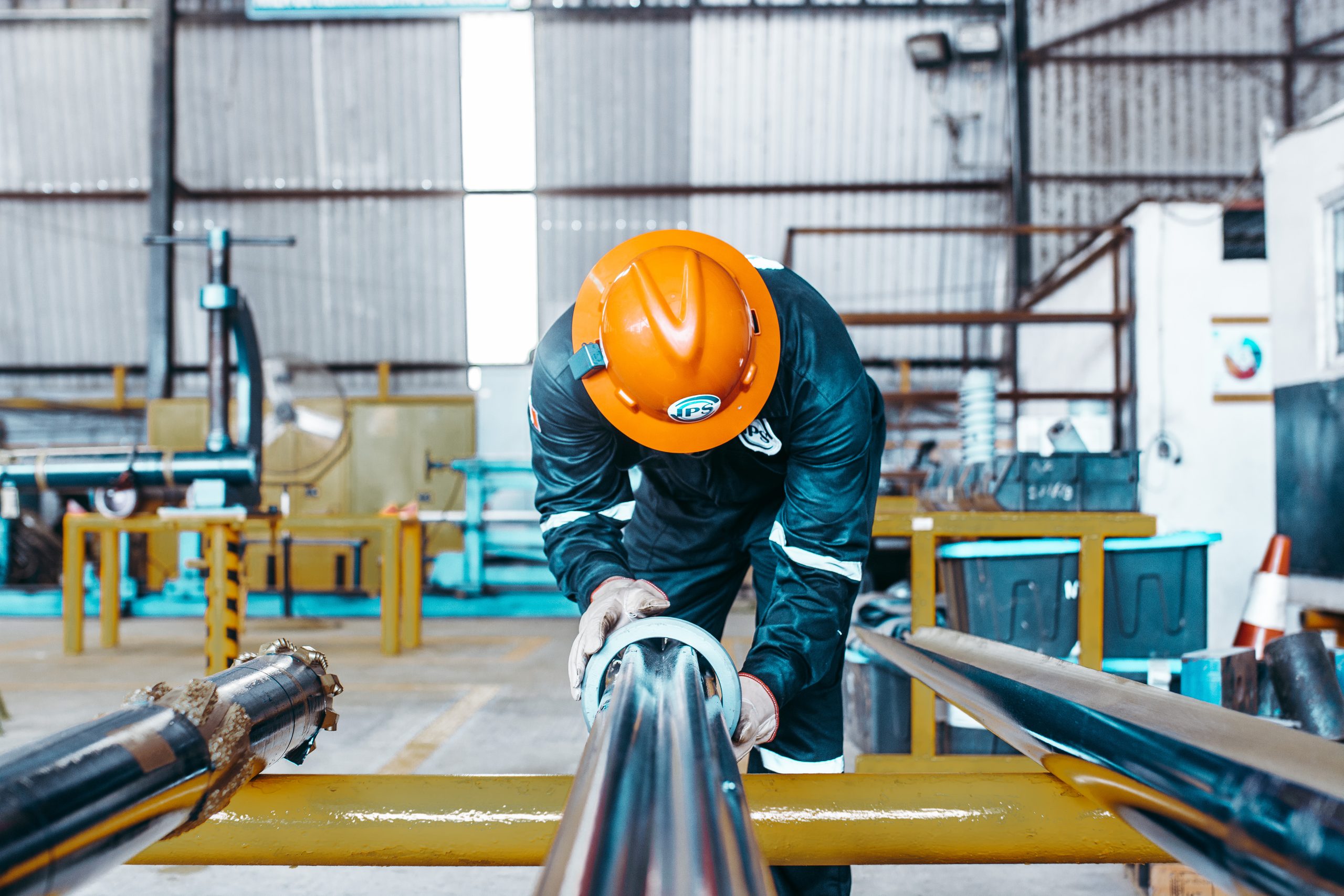 Technician in an orange hard hat inspecting pipe in the workshop
