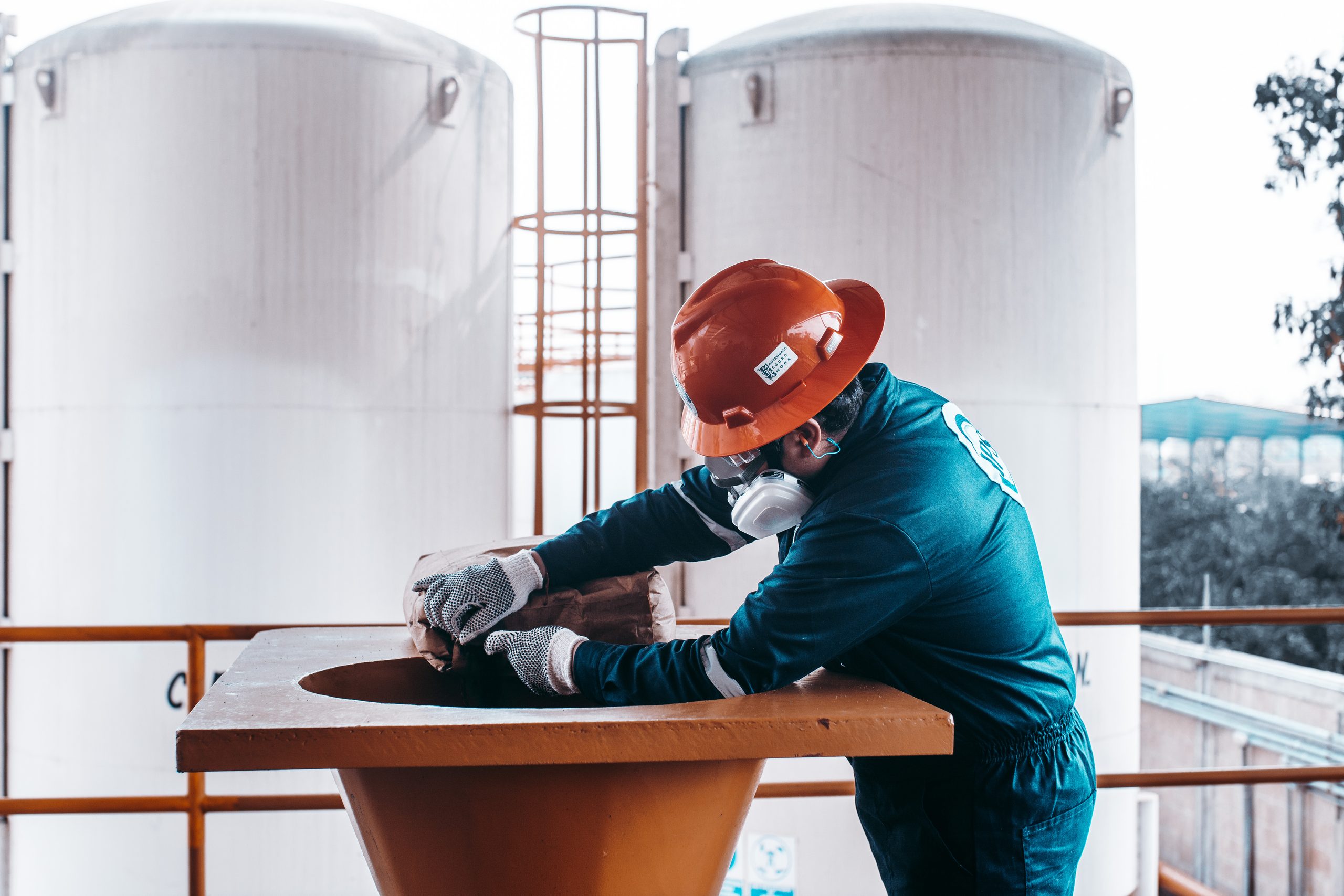 Technician in a respirator handling material at a storage tank