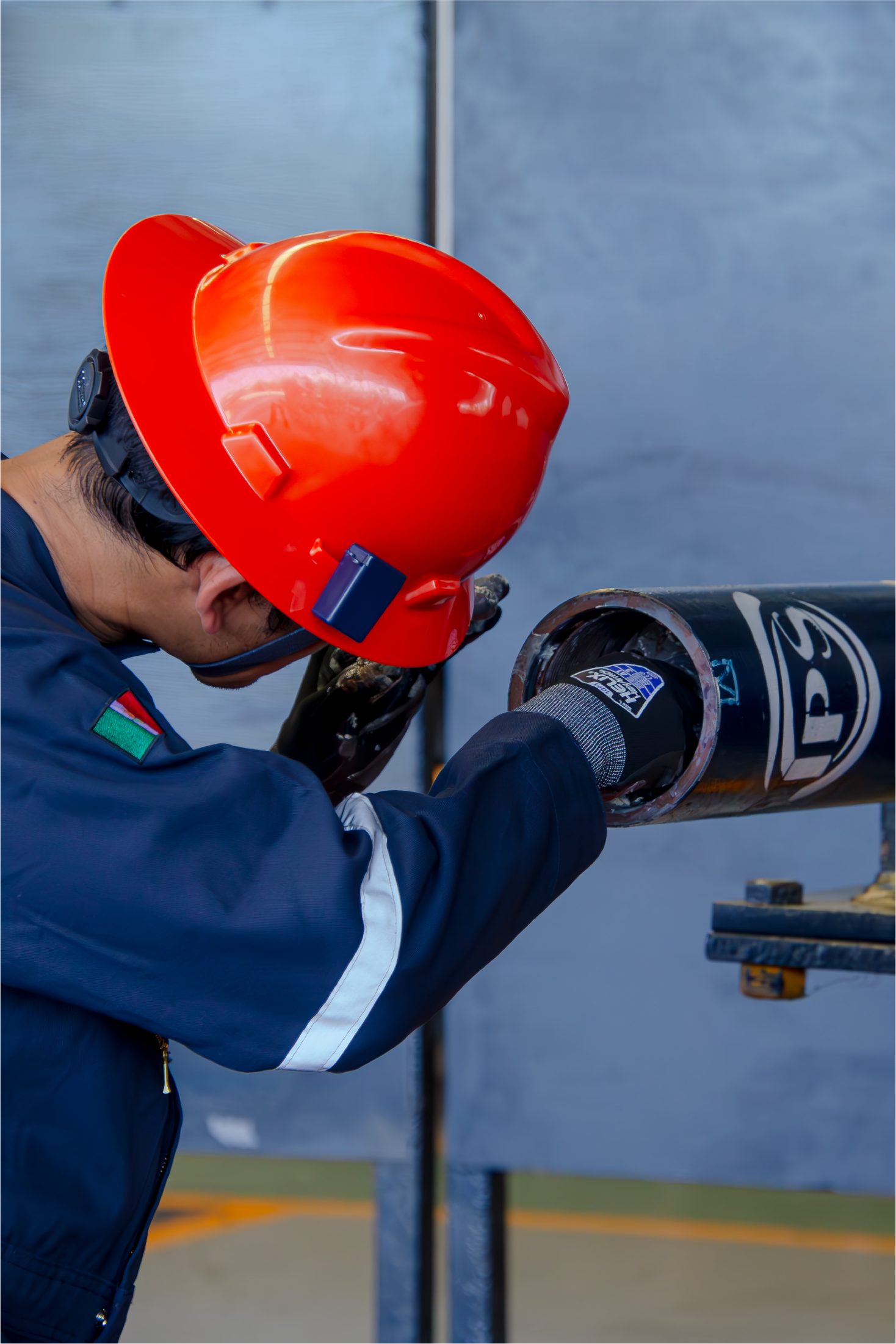 Technician in a red hard hat servicing a drilling jar