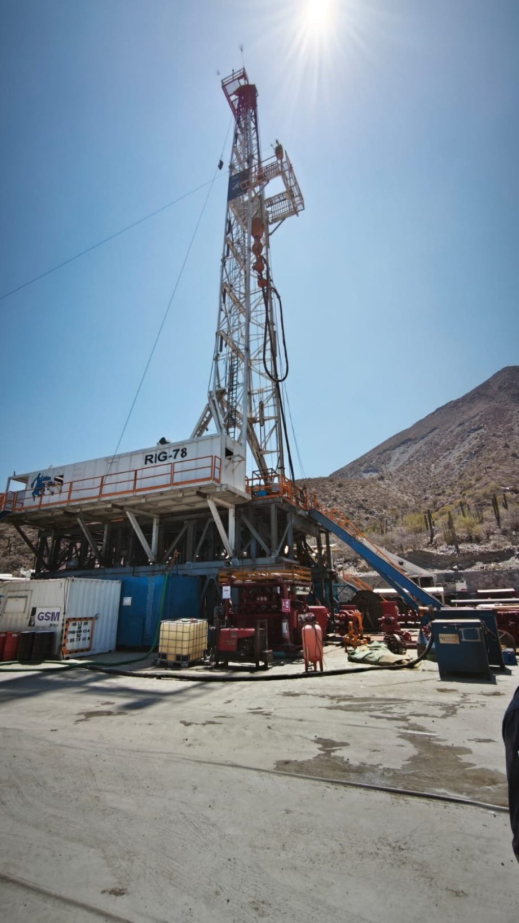 Drilling rig on a desert well pad under a clear sky