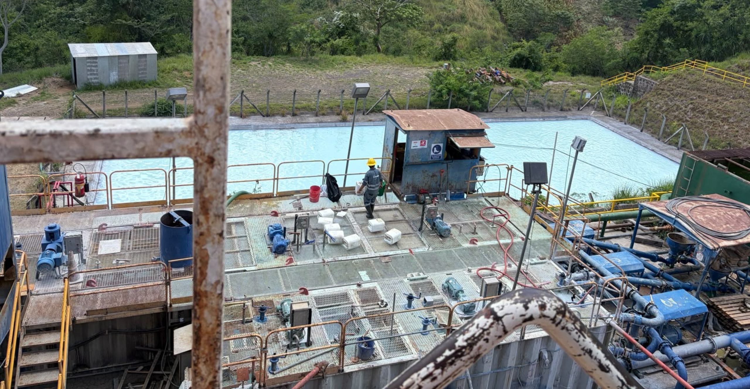 Well testing equipment and pipework beside a geothermal water pond