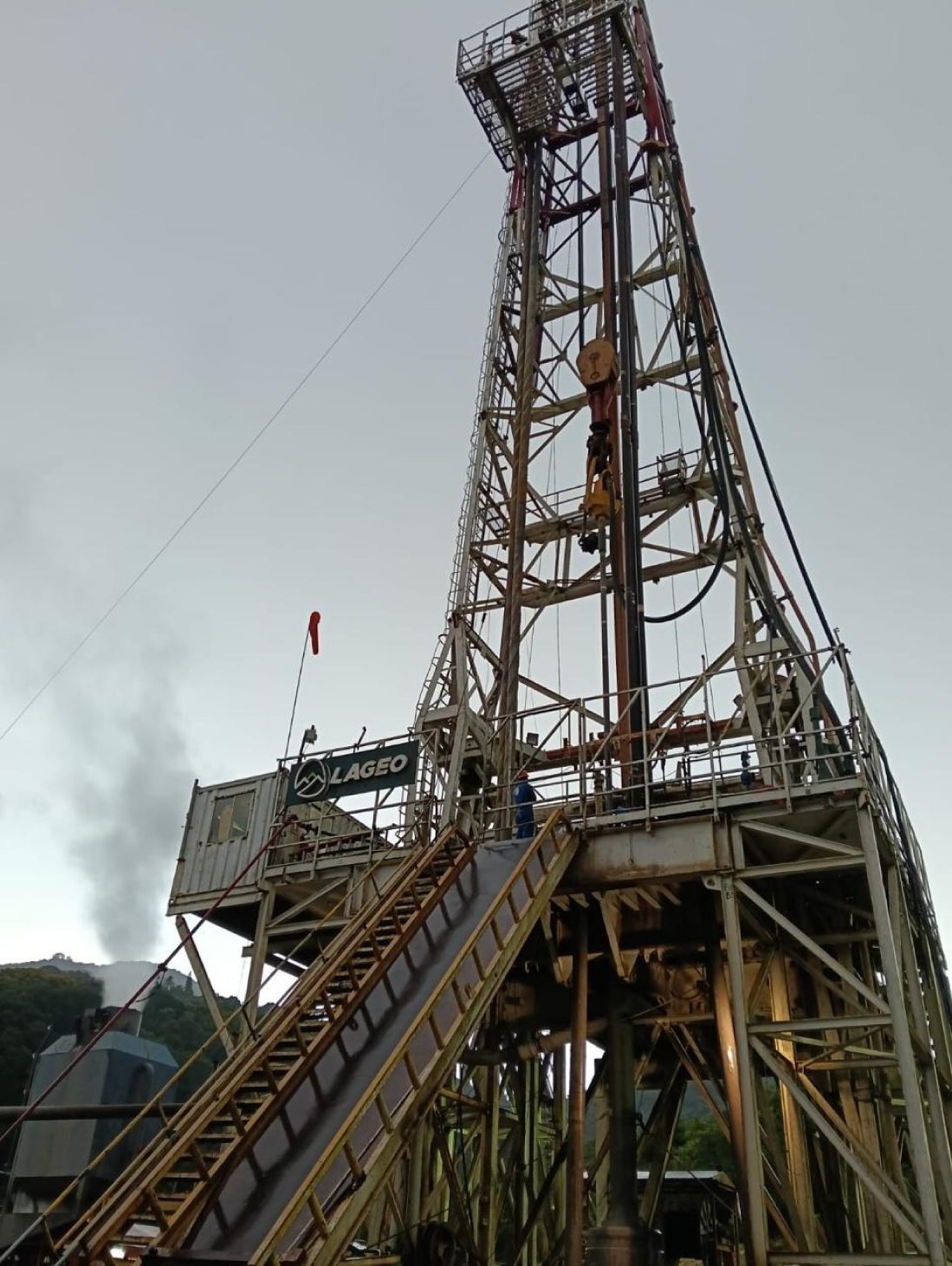 Drilling rig with steam rising from a geothermal well