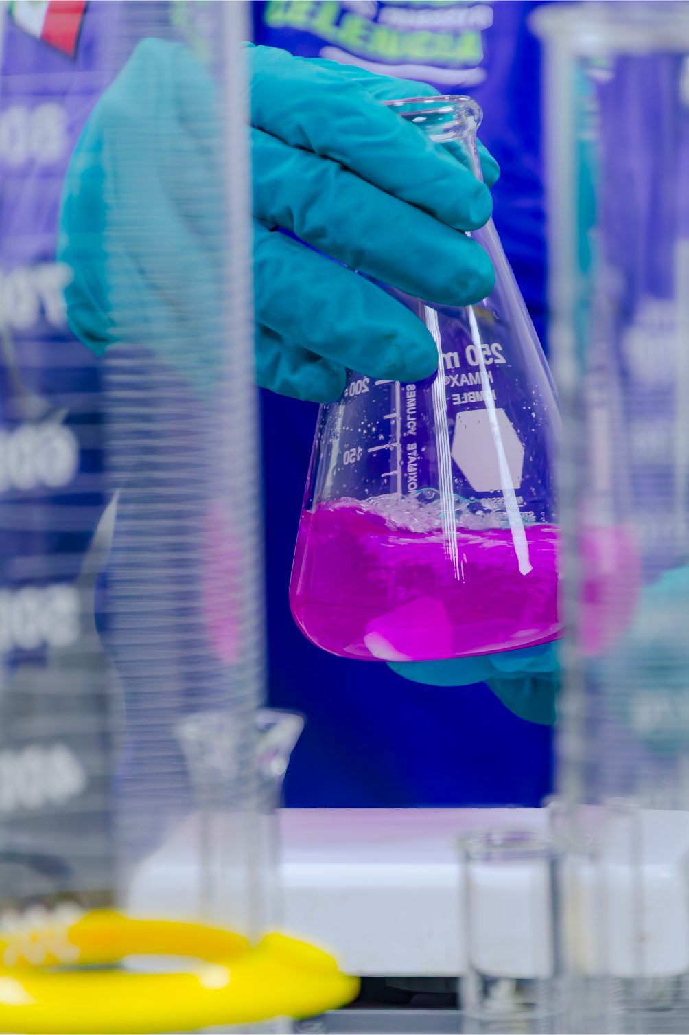 Gloved hand holding a flask of pink fluid in the laboratory